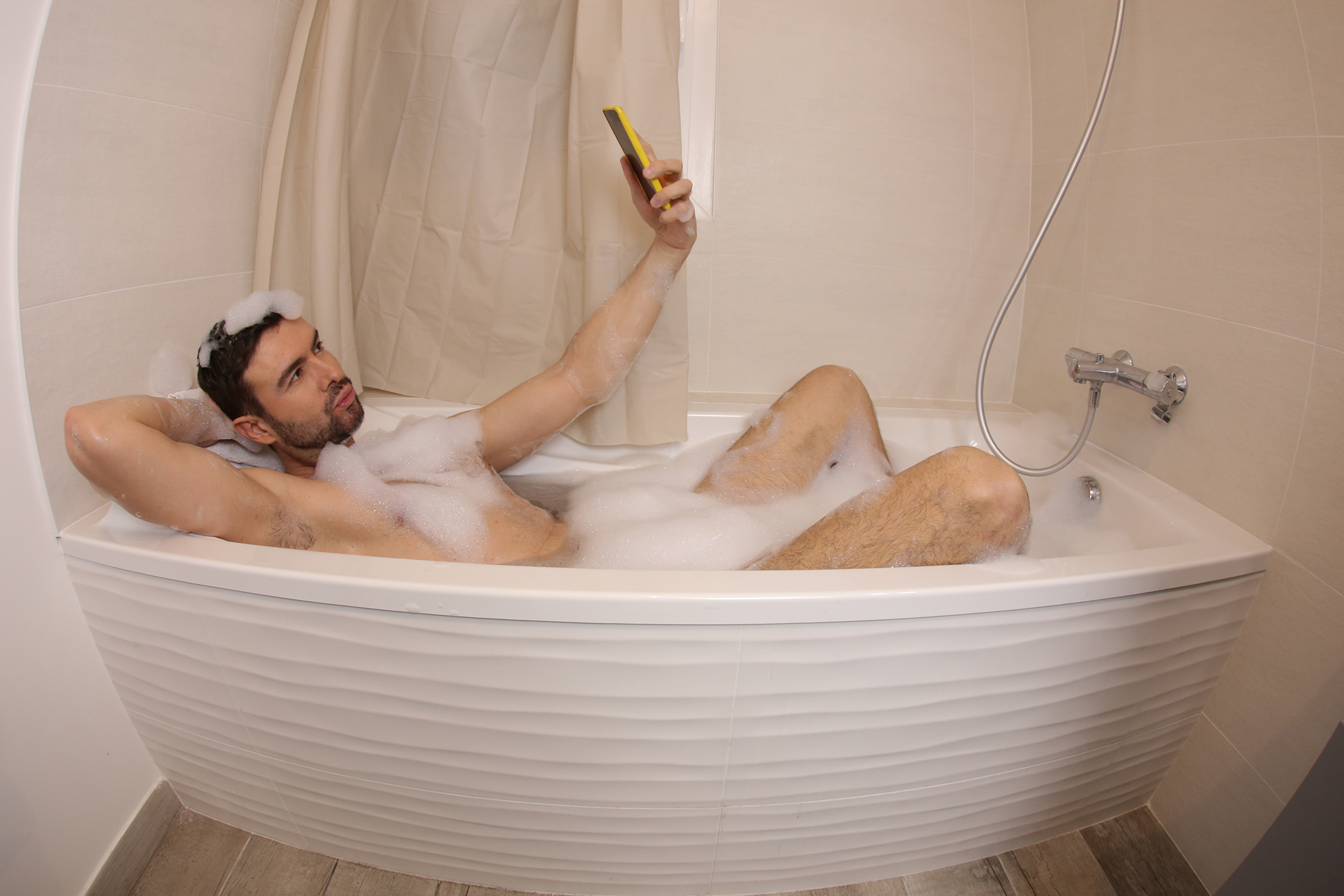 Attractive man taking a selfie in the bathtub